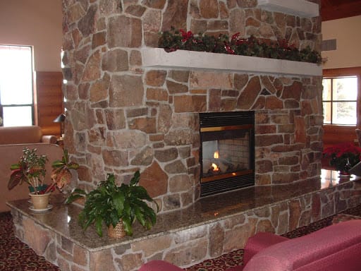 A cozy room featuring a stone fireplace with decorative plants and a mantel.