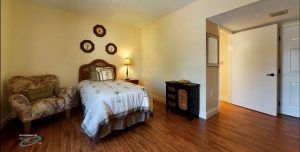 A cozy bedroom with a single bed, warm lighting, and wooden flooring.