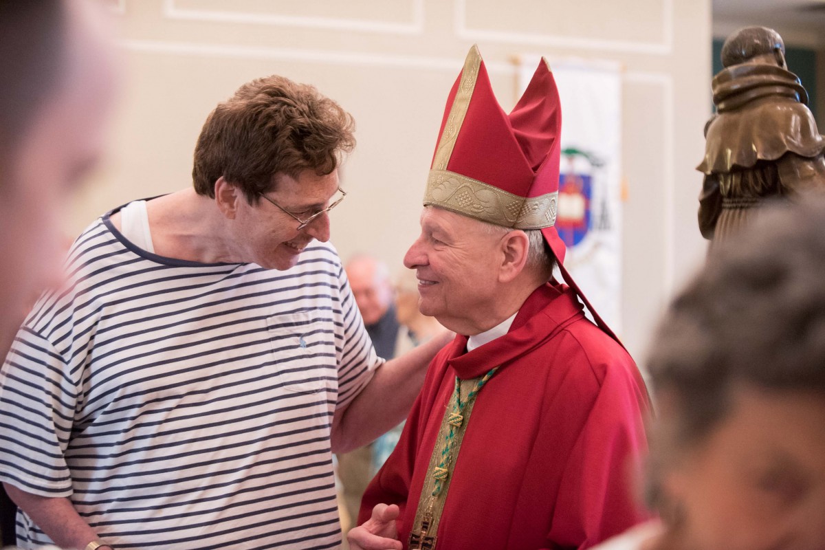 A friendly interaction between a man in casual clothing and a bishop in traditional religious attire.