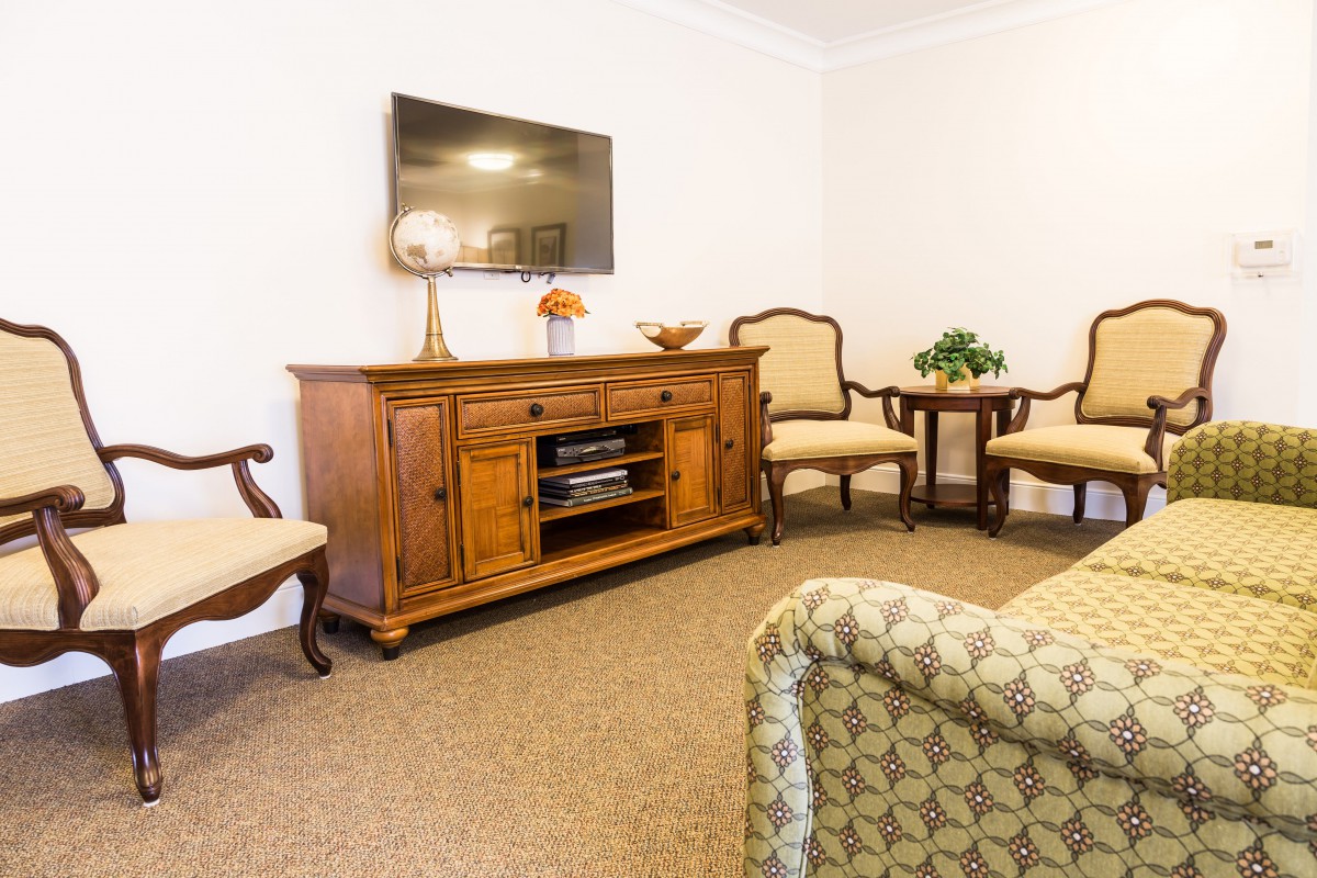 A cozy living room with classic wooden furniture and a wall-mounted television.