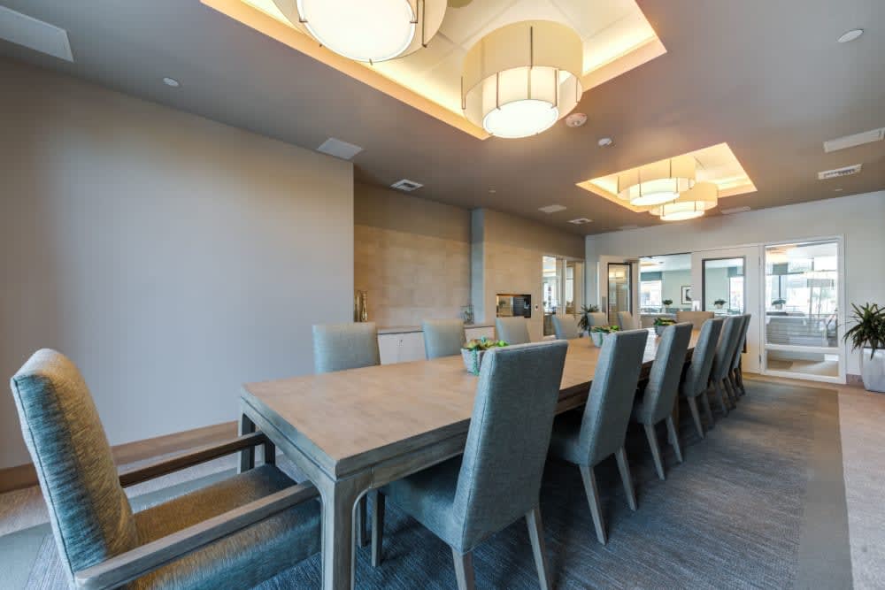 A modern dining room with a large table and elegant chairs, featuring stylish ceiling lights.