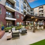 A modern apartment complex with an inviting outdoor seating area and garden.
