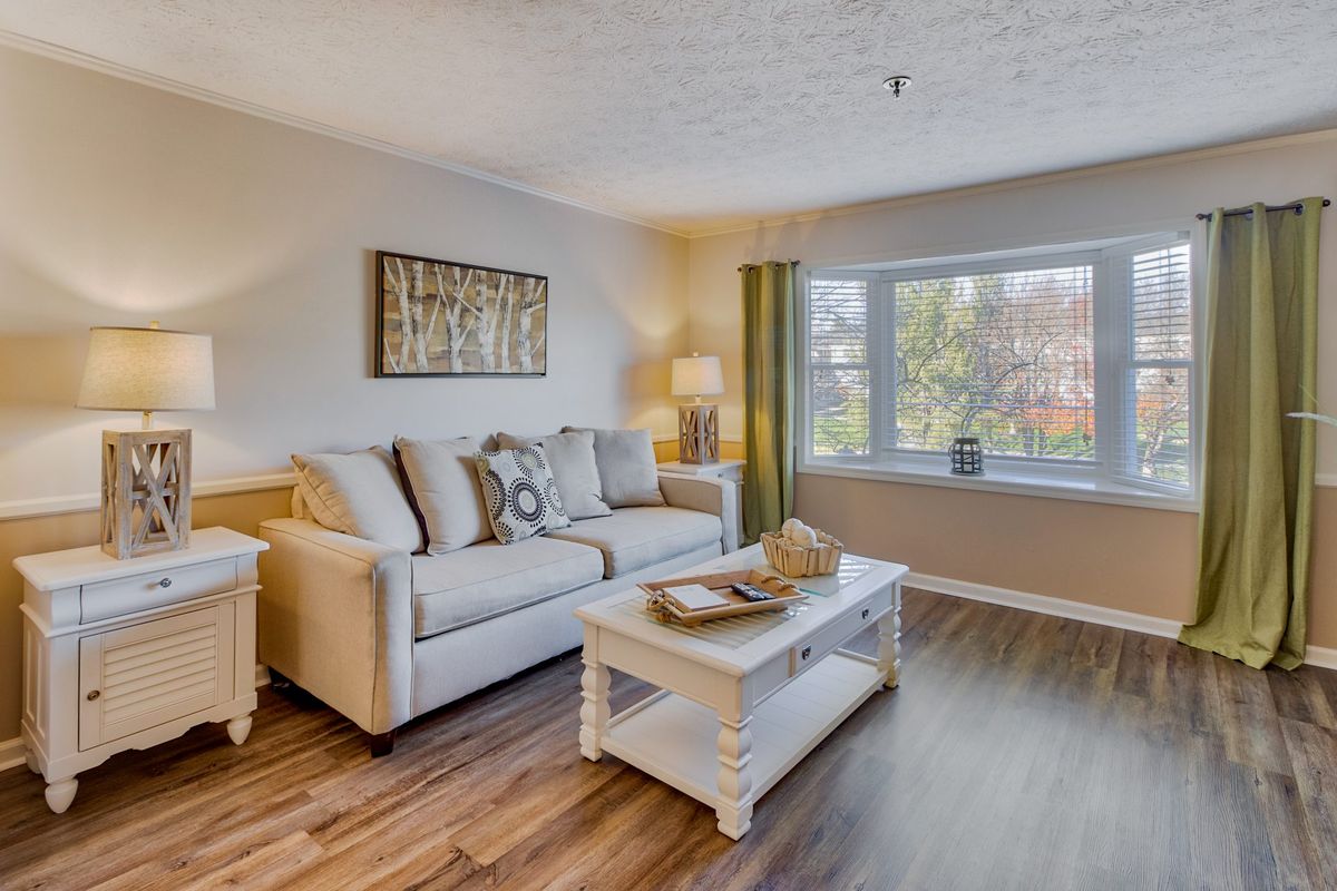 A cozy and well-decorated living room with a comfortable sofa, coffee table, and large window.