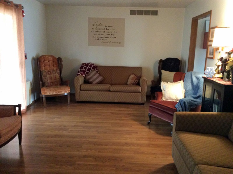 A cozy living room with a sofa, armchairs, and wooden flooring.