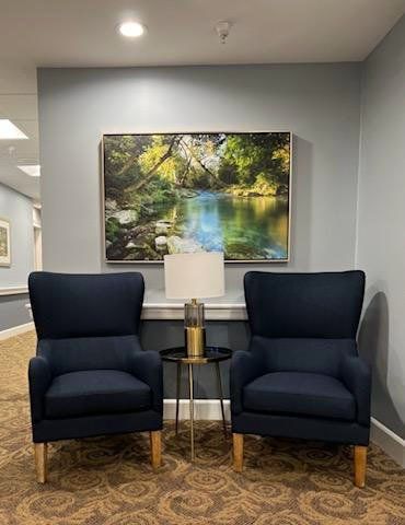 A cozy seating area with two navy armchairs and a nature-themed painting.