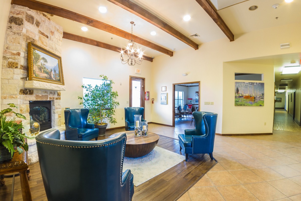 A cozy living room with modern decor, featuring blue chairs, wooden beams, and a chandelier.