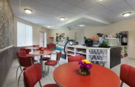 A cozy caf interior featuring round tables and bright red chairs, adorned with colorful floral centerpieces.