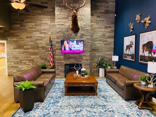 A cozy living room featuring leather sofas, a deer mount above the fireplace, and modern decor elements.