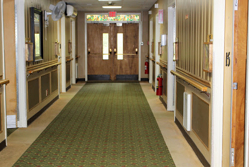 A well-lit indoor hallway leading to double doors, featuring a patterned carpet and safety equipment.