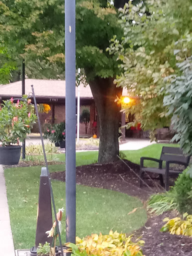 A serene park scene at sunset, featuring a cozy bench surrounded by lush greenery.