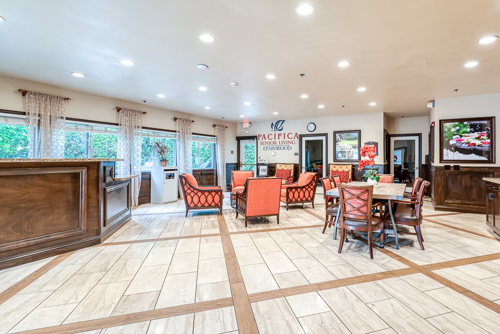 A spacious and modern dining area with multiple tables and chairs, well-lit with large windows.