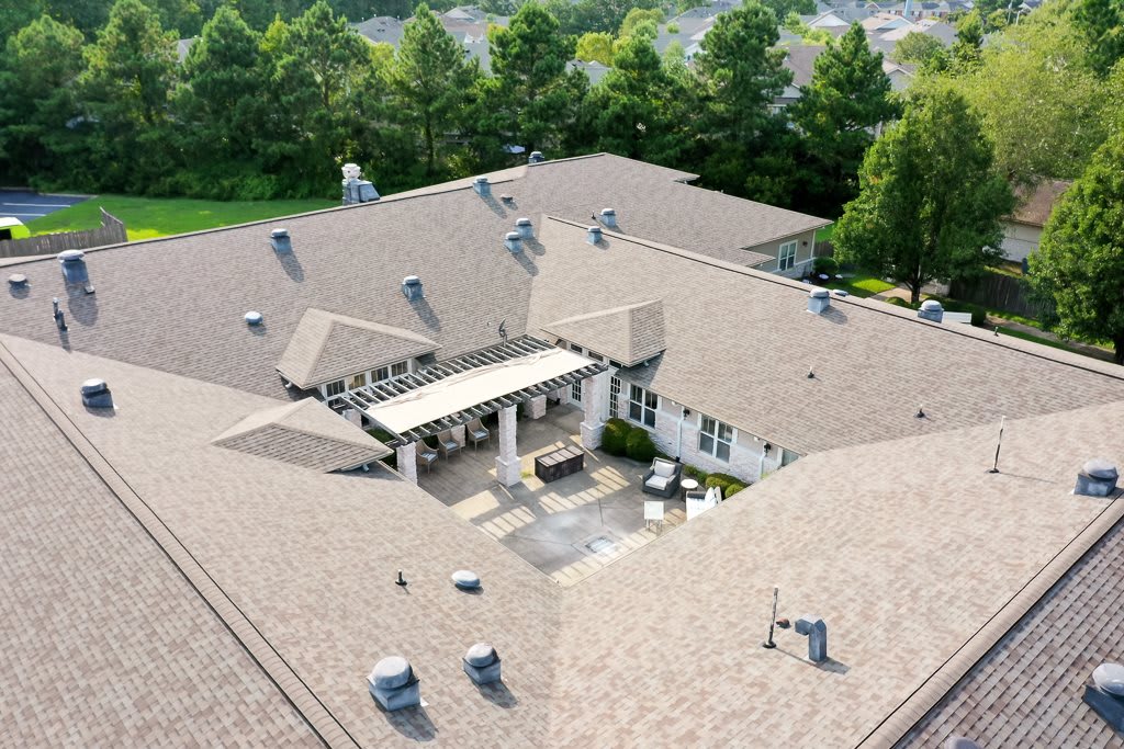 Aerial view of a large building with a central courtyard surrounded by lush trees.