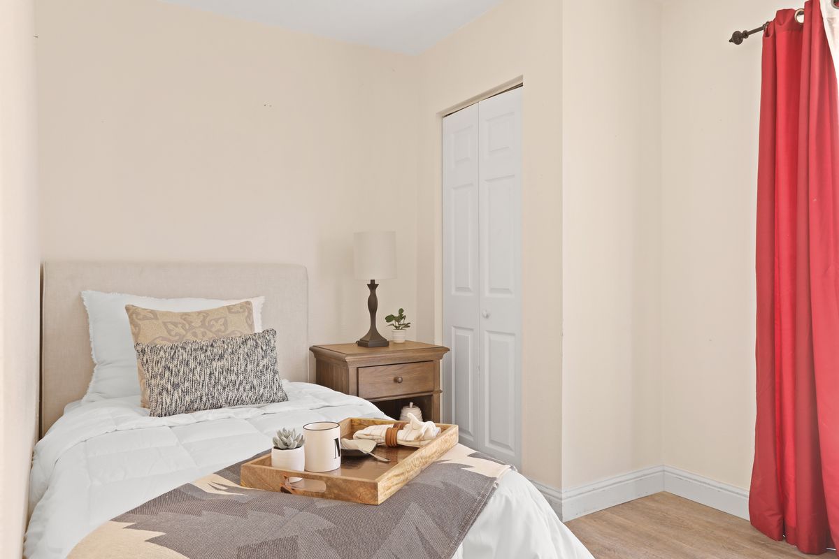 A cozy bedroom with a bed, nightstand, lamp, and decorative tray.