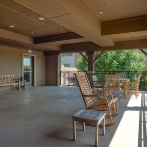 A covered balcony area with wooden chairs and benches for relaxation.