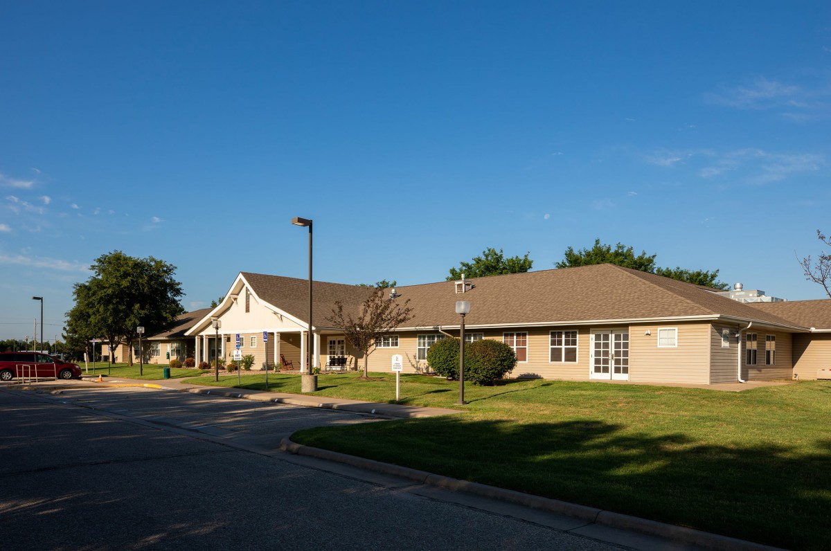 A suburban residential building with a neatly maintained lawn under a clear blue sky.