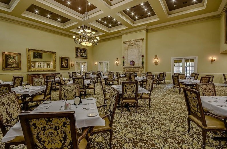 An elegant and spacious dining room with chandeliers, set up for formal dining.