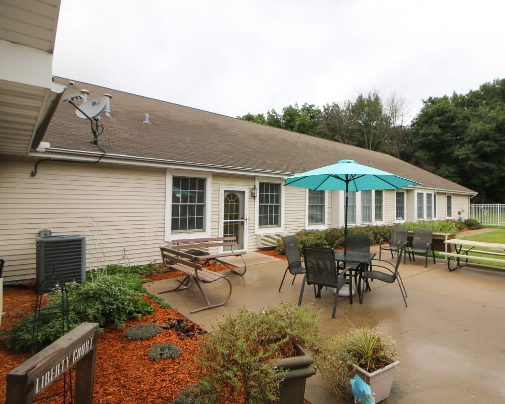 A cozy patio setup with tables, chairs, and an umbrella outside a house.