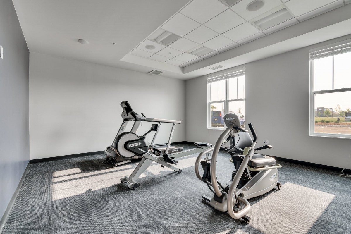 A bright gym room featuring treadmills and other exercise equipment.