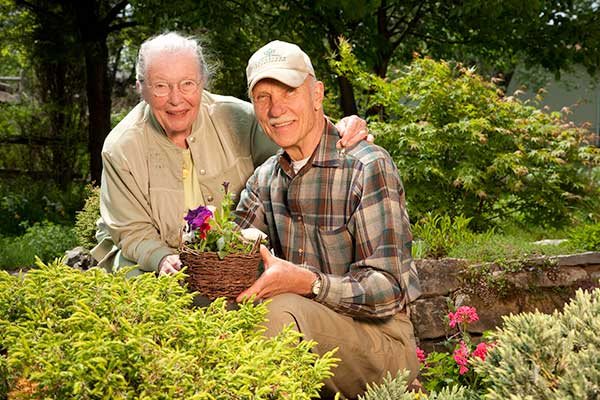 An elderly couple enjoys gardening together outdoors.