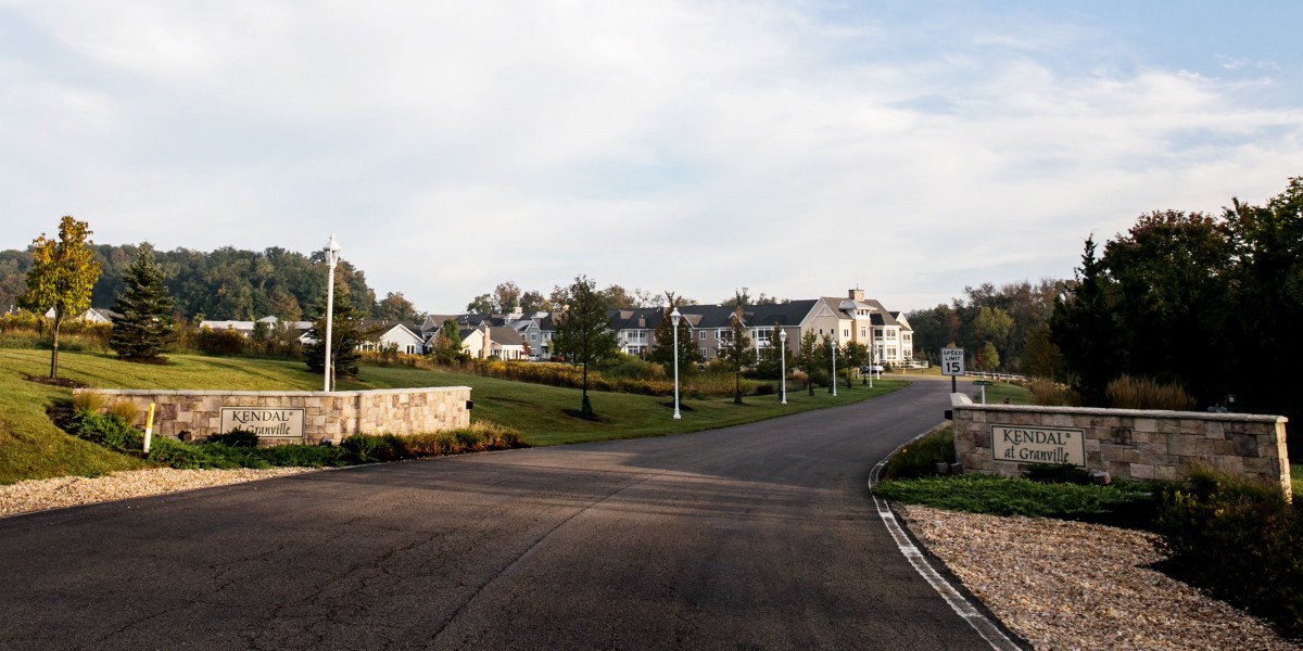 A quiet suburban neighborhood with neatly lined houses and streetlights along a winding road.