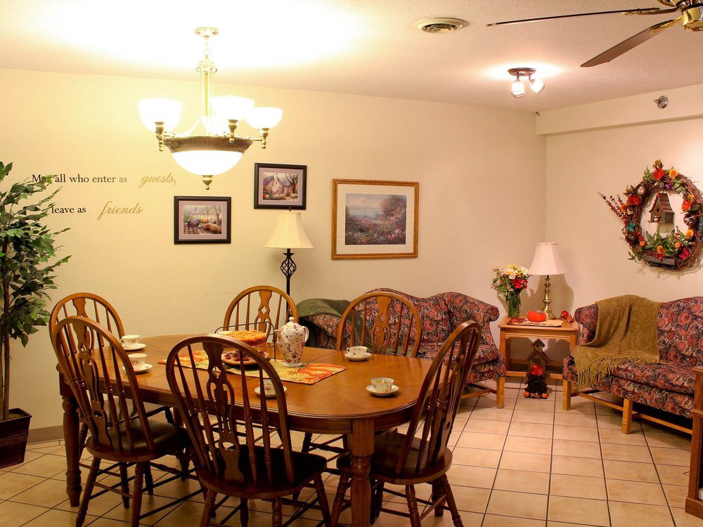 A cozy dining room with a wooden table and chairs, decorated with wall art and lit by a chandelier.