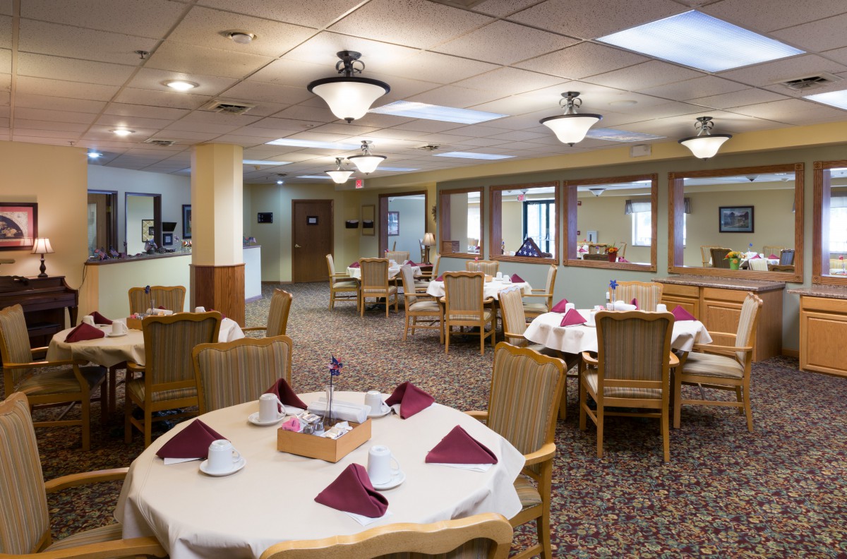 An elegantly set dining room with neatly arranged tables and chairs, featuring warm lighting and decor.