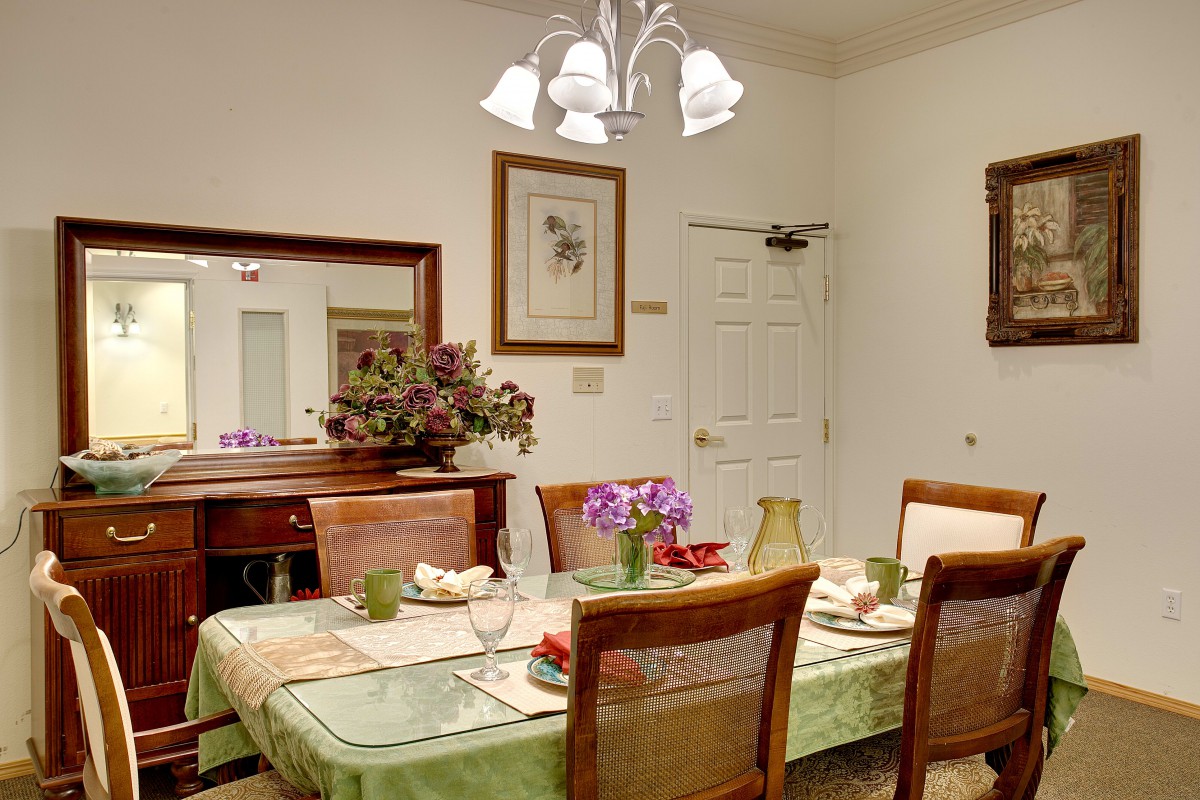 A neatly arranged dining room with a decorated table, featuring flowers and elegant lighting.