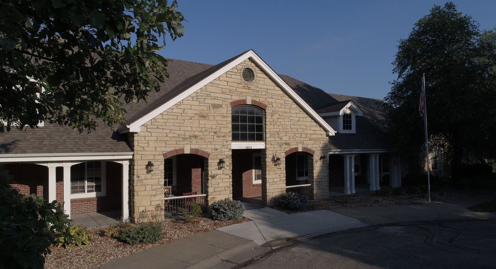 A stone-exterior residential building with a prominent entrance and windows, set against a clear sky.