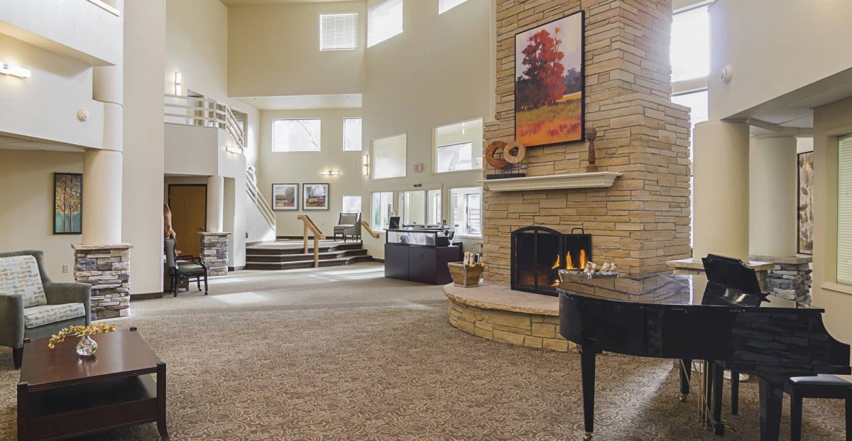A spacious living room featuring a fireplace, grand piano, and large windows that let in natural light.