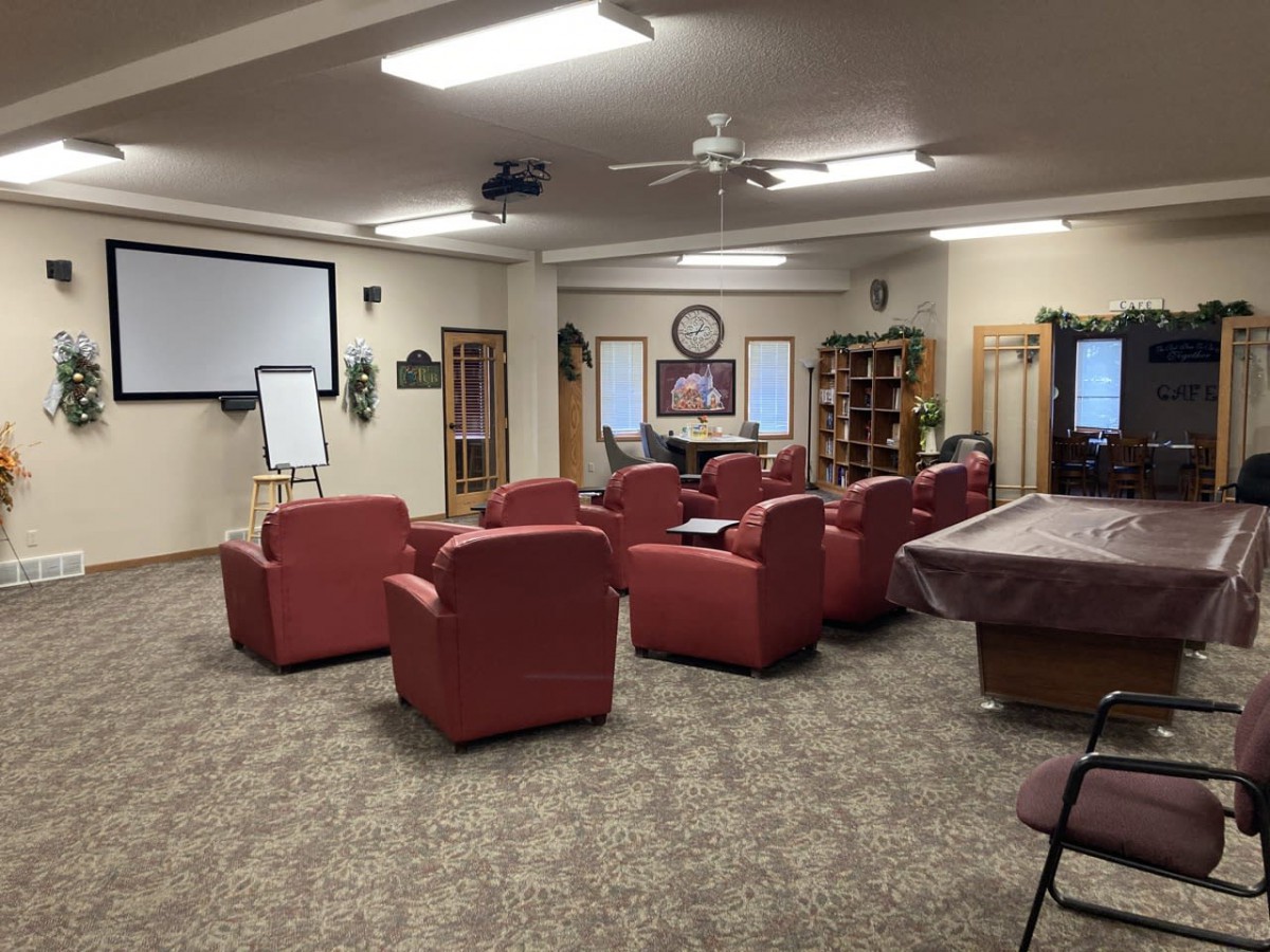 A conference room with red chairs arranged facing a projector screen and flip chart.