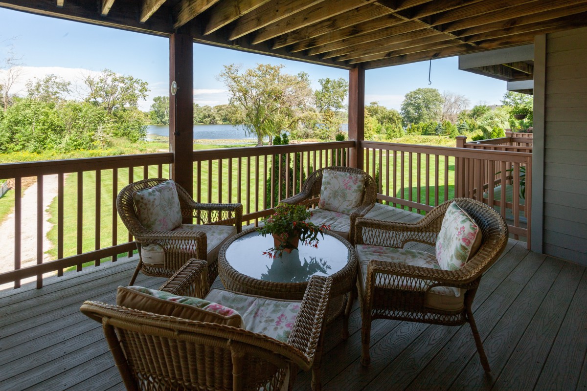 A cozy outdoor patio with wicker furniture overlooking a scenic landscape.