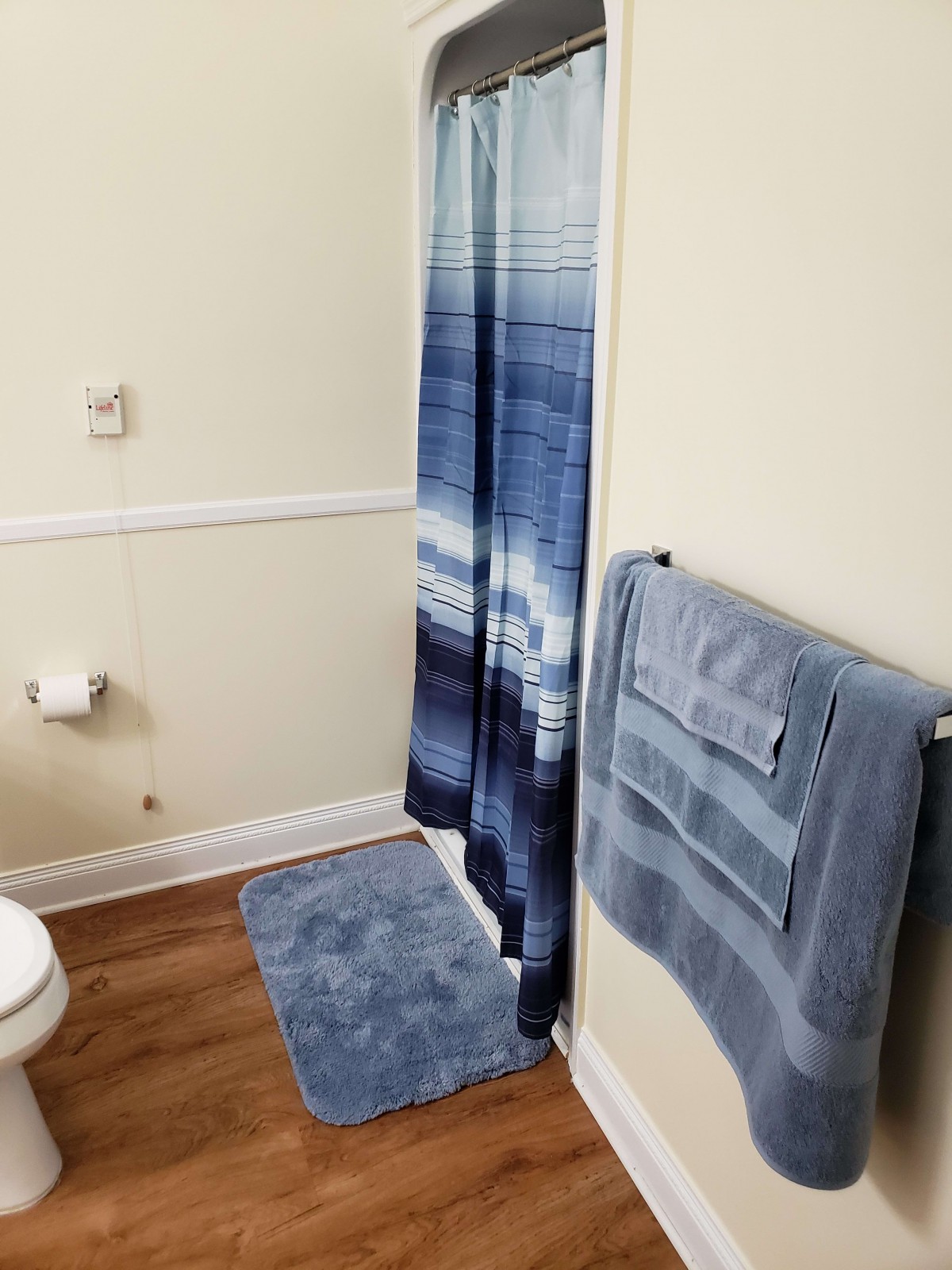 A neatly arranged bathroom with a blue-themed shower curtain, towels, and rug.