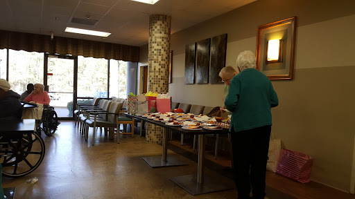 Senior citizens enjoying a community gathering in the lobby with refreshments on display.