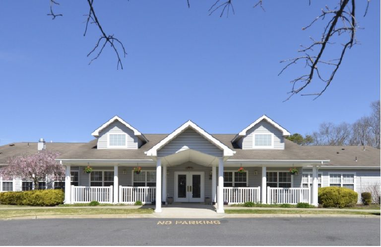 A symmetrical single-story residential building with a pitched roof and a front porch under a clear blue sky.