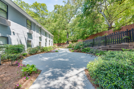 A serene pathway bordered by lush greenery and a modern building.