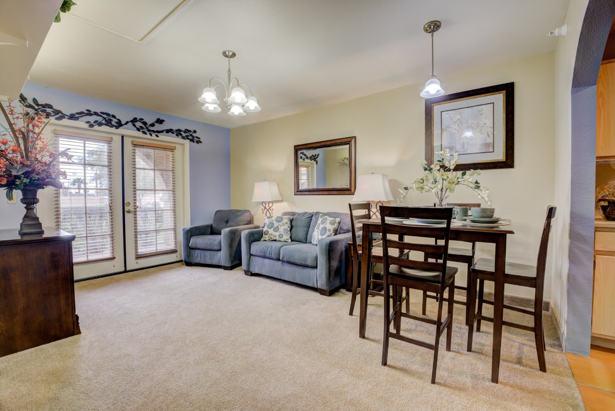 A cozy living and dining space with a sofa, armchairs, and a dining table set under warm lighting.