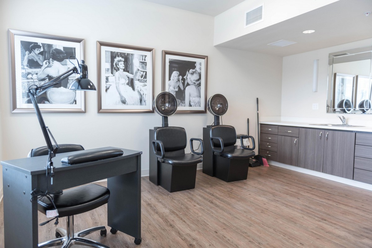 Modern beauty salon interior with hair drying stations and portraits on the wall.