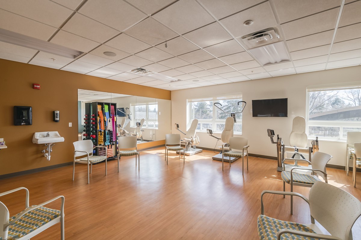 A bright and spacious waiting room with chairs, a television, and a vending machine.