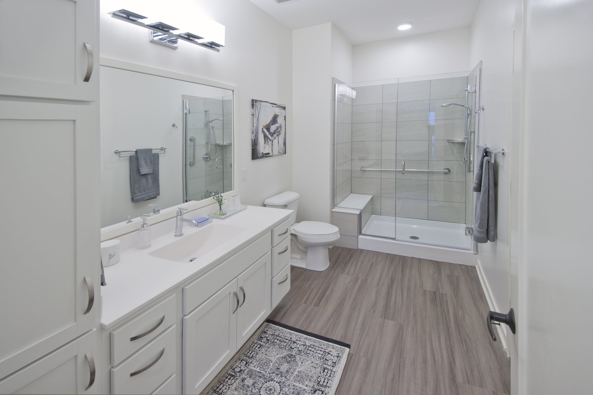 A modern bathroom with a double sink vanity, walk-in shower, and minimalist design.