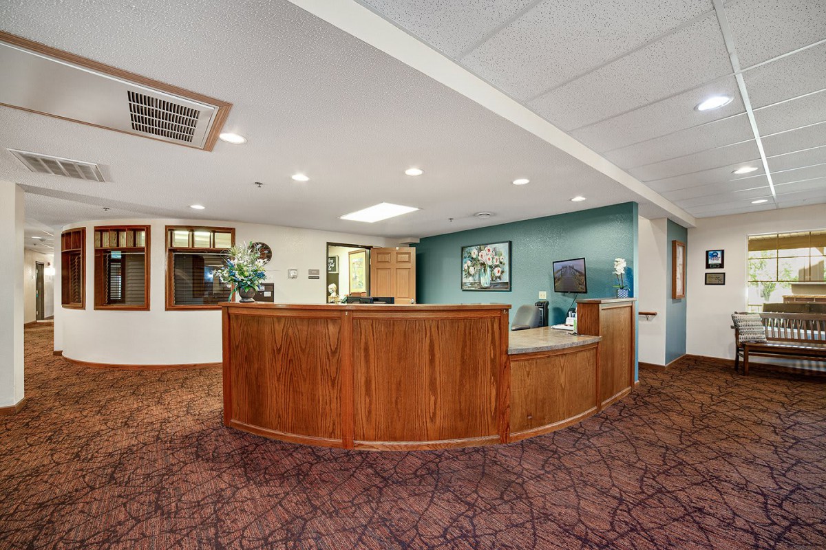 A well-lit office reception area with a wooden desk and comfortable seating.