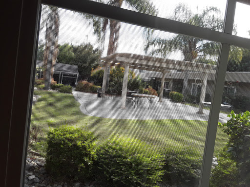 A serene outdoor garden area featuring a patio with a pergola and lush greenery.