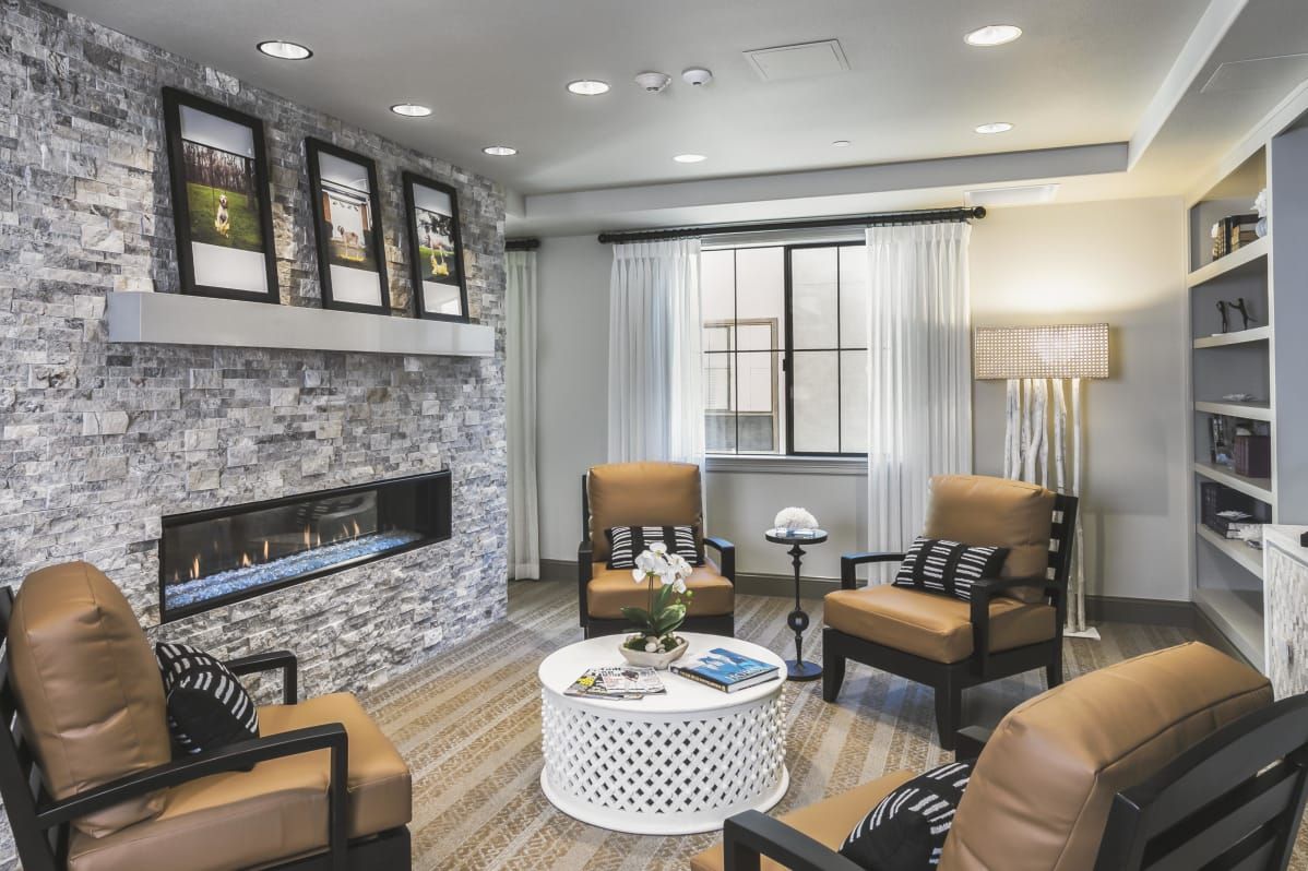 A modern and cozy living room with a stone fireplace, comfortable armchairs, and contemporary decor.