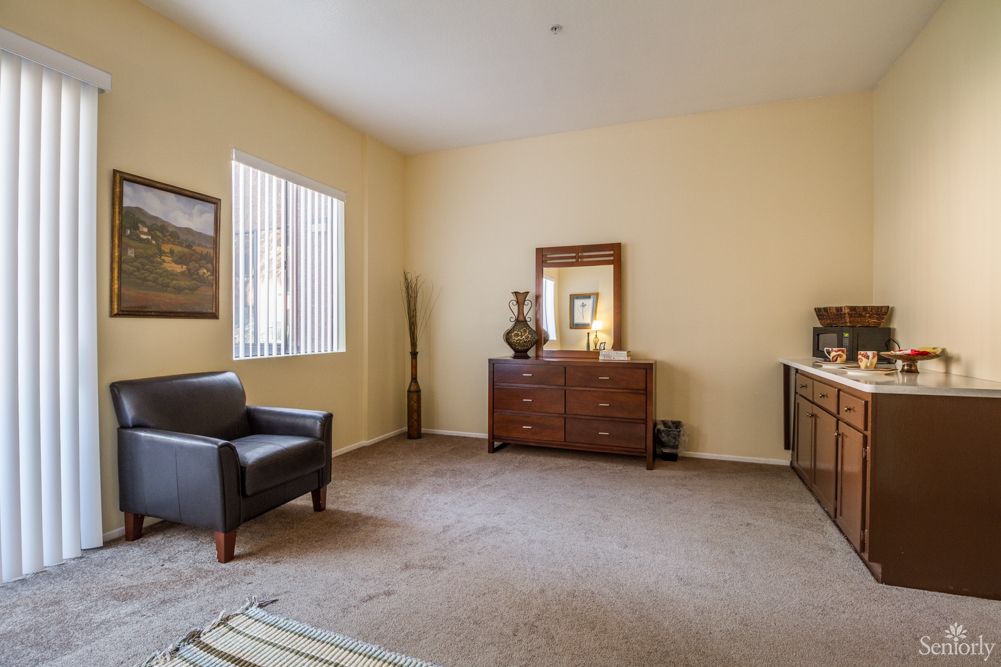A cozy living room with an armchair and a dresser adorned with decor.