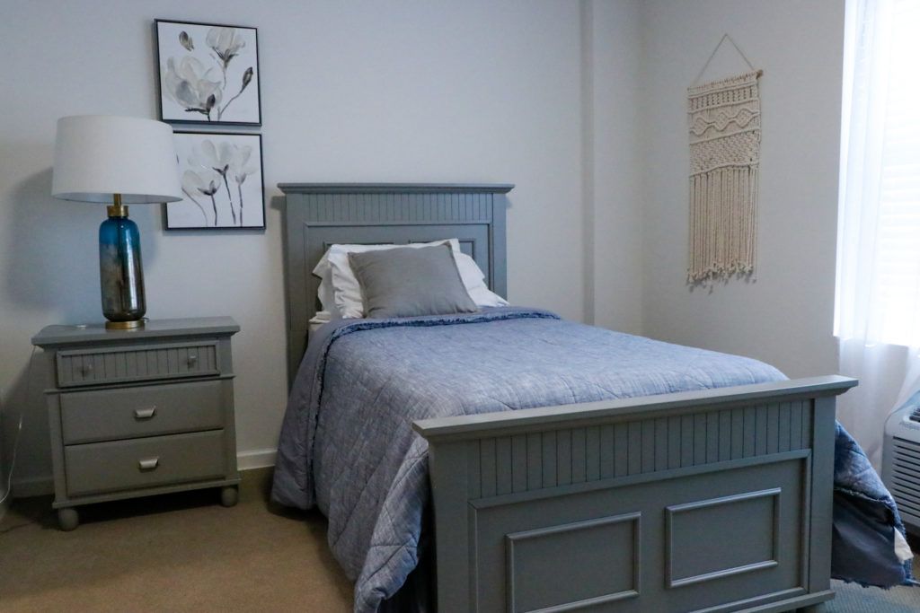 A simple and elegant bedroom with a single bed, blue bedding, and minimalist decor.