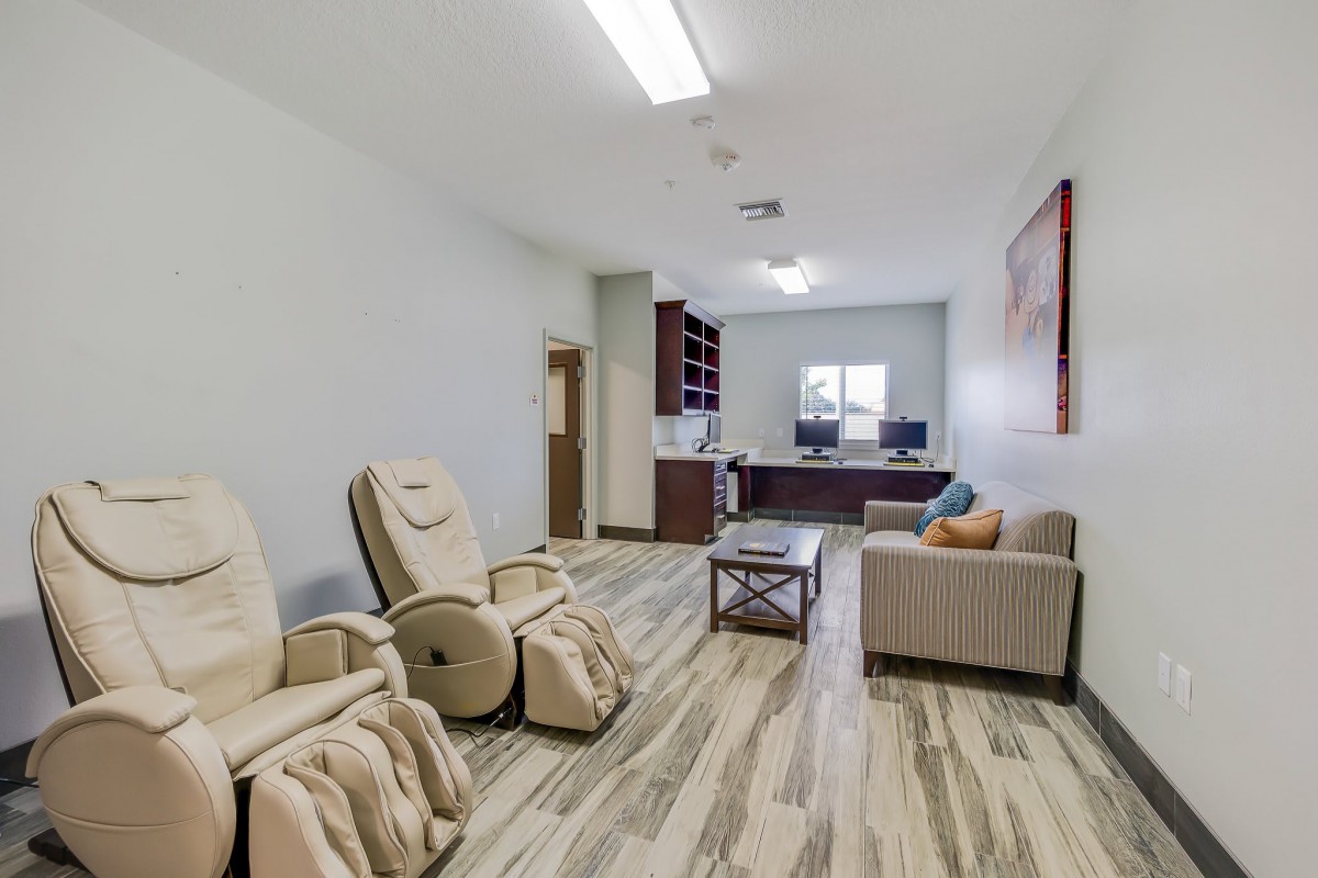 A modern reception area with massage chairs and a sofa, featuring comfortable seating and ample lighting.