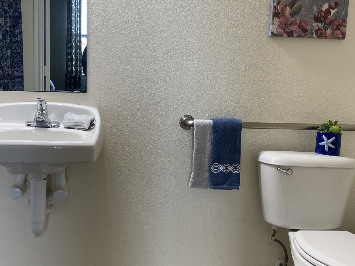 A small bathroom with a sink, mirror, toilet, and a towel hanging on a rack.