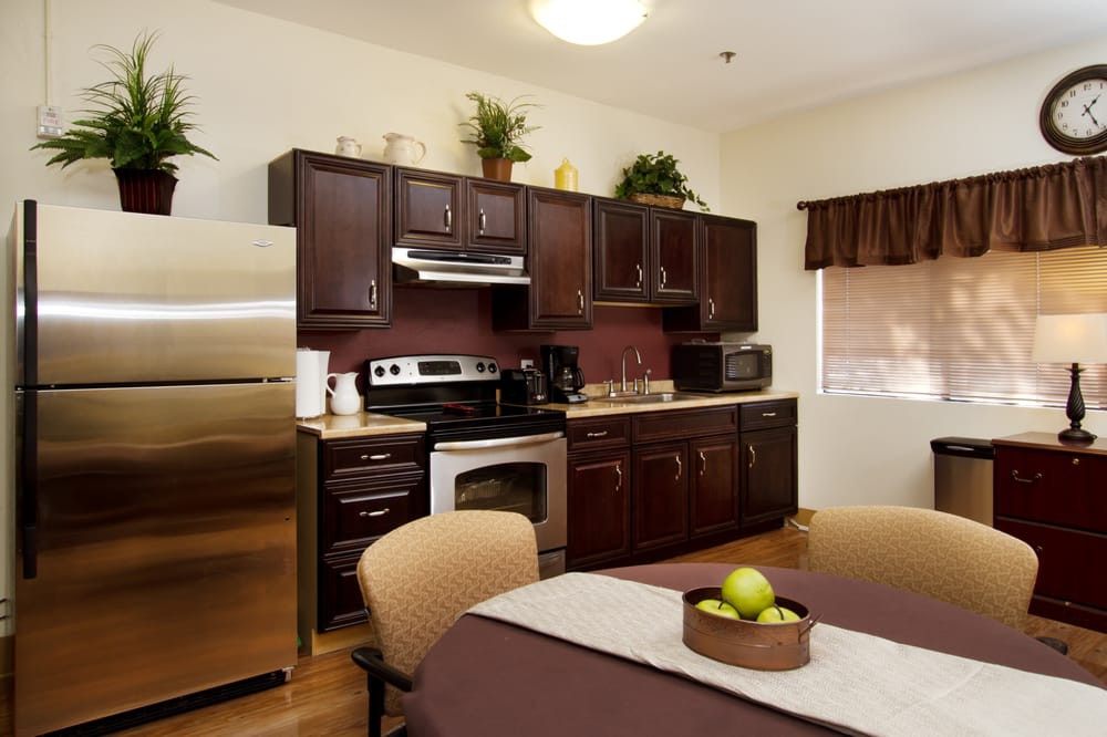 A modern kitchen with dark wood cabinets, stainless steel appliances, and a dining area.