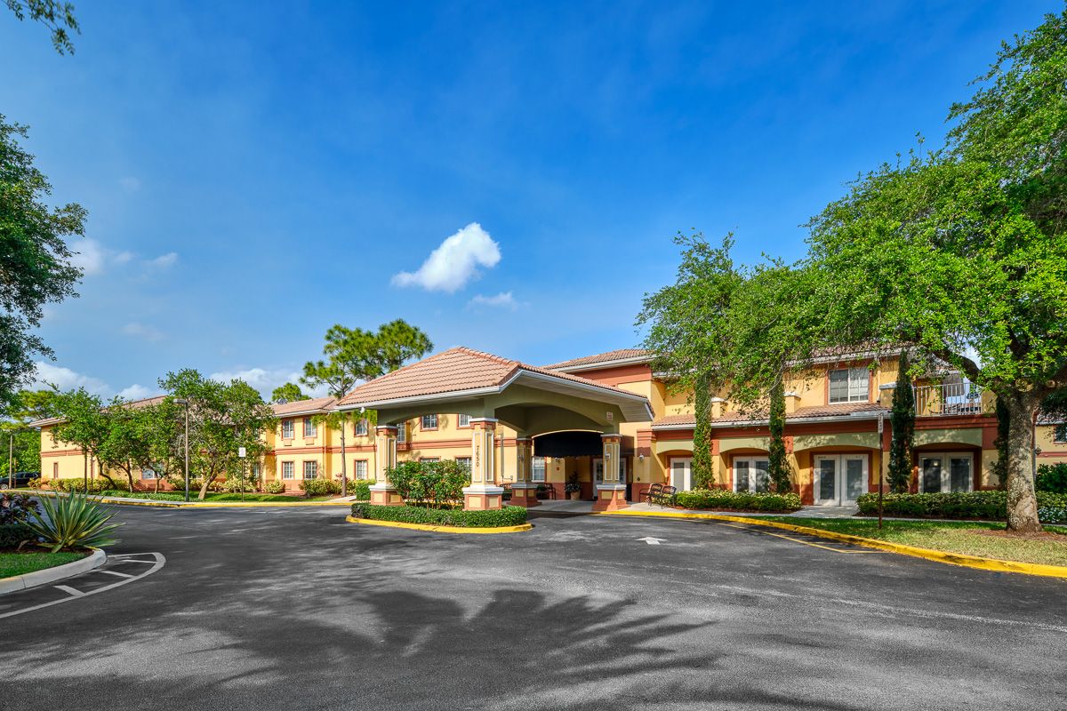 A sunny day view of a hotel entrance surrounded by trees.