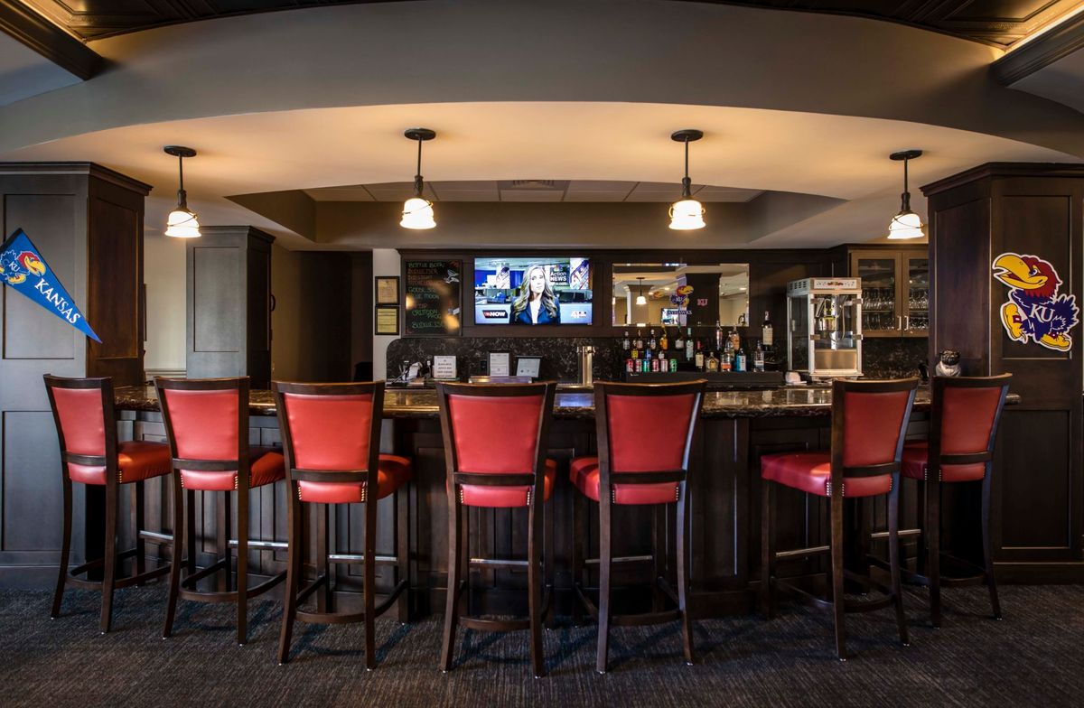 An empty bar with red chairs and pendant lighting.