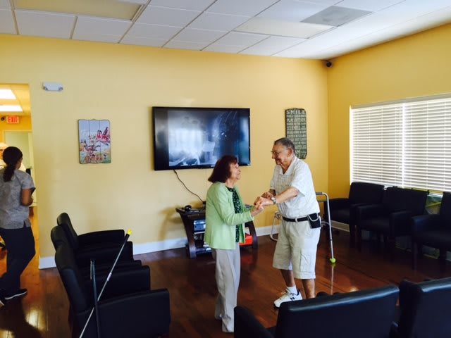 Two seniors dancing together in a living room.
